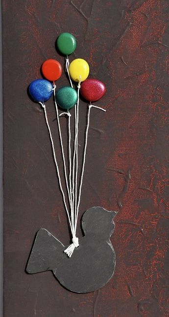 Un uccellino nero sollevato da un grappolo di palloncini colorati