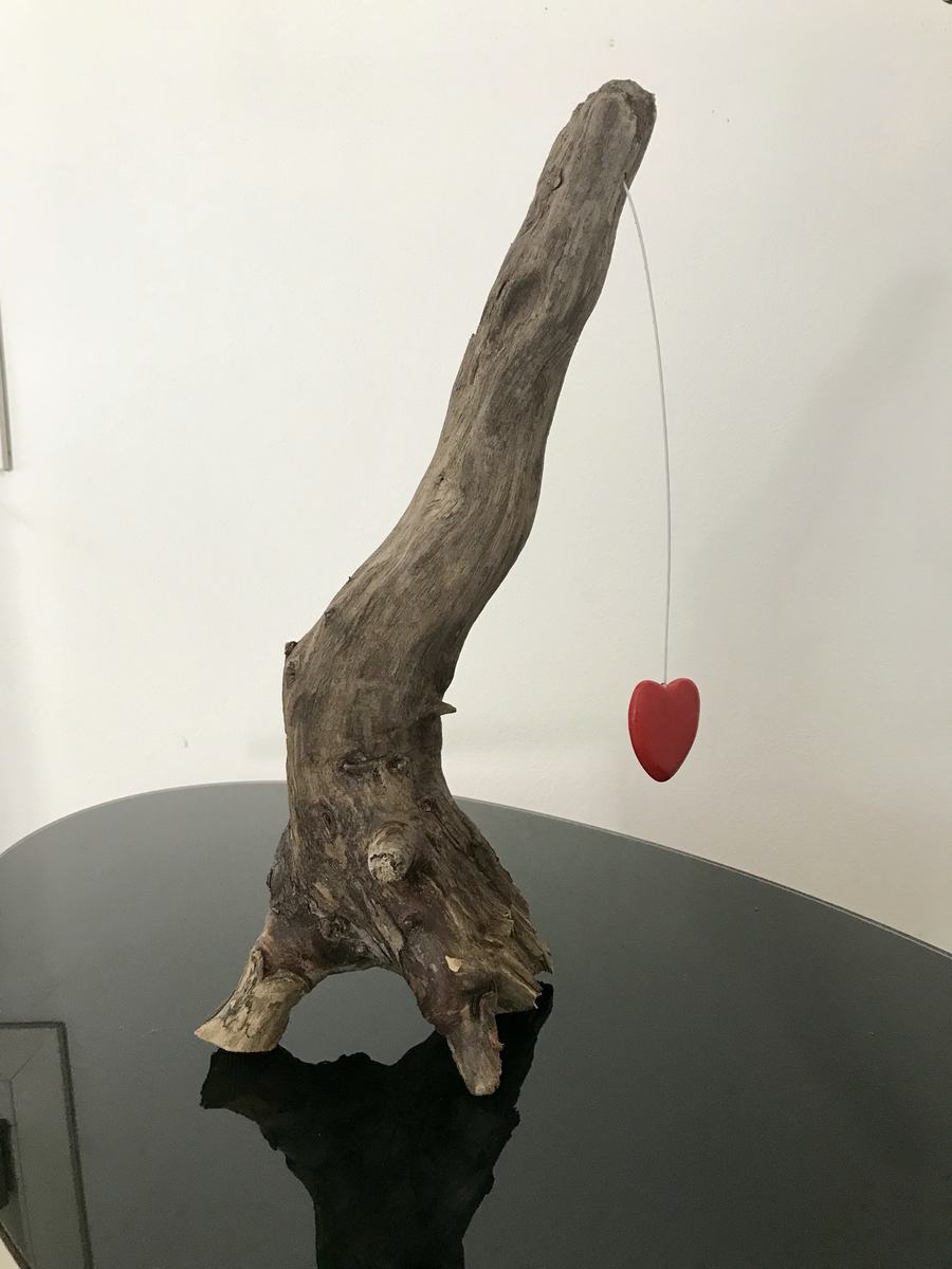 Un ramo di legno con un cuore rosso appeso a un filo