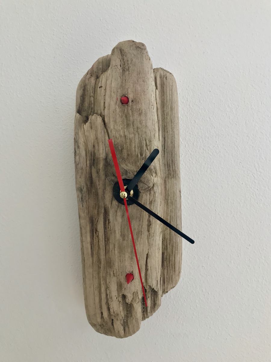 Orologio ricavato da un pezzo di legno, con lancette nere e rosse