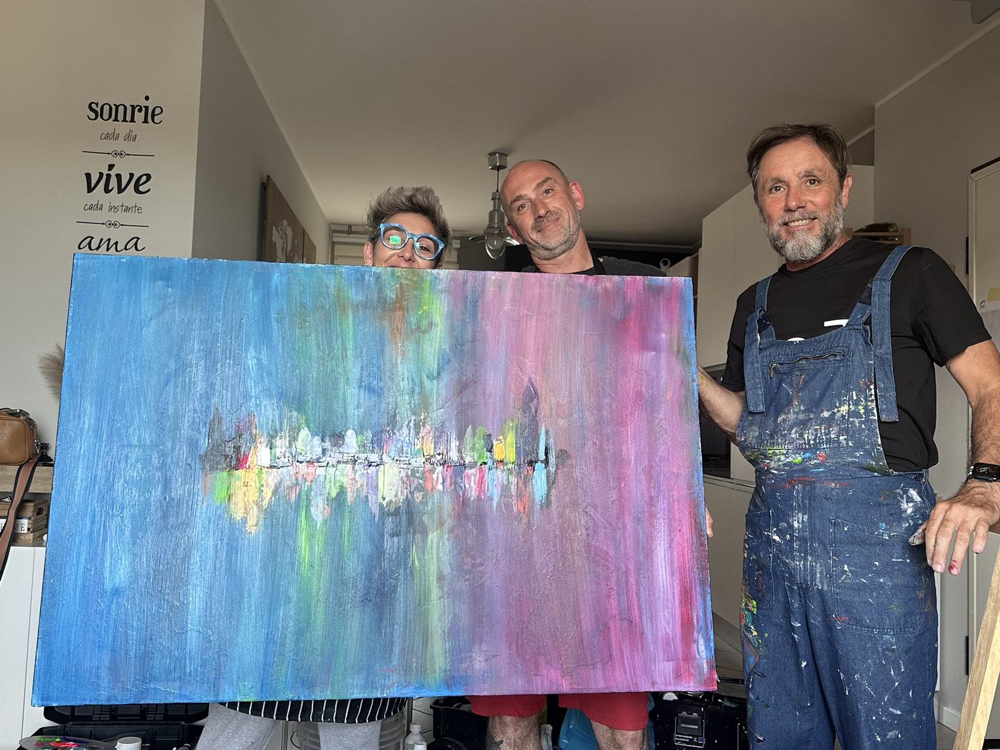 Due persone mostrano il quadro appena finito, azzurro e rosa